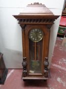 An early twentieth century beech wall clock with pendulum and brass dial