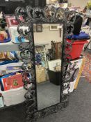 A cotemporary bevel-edged hall mirror, in an elaborate black metal foliage design frame,