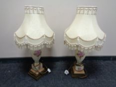 A pair of hand painted porcelain table lamps on brass bases with tasselled shades