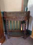 An Edwardian oak demi lune hall table on barley twist legs with bergere back and undershelf