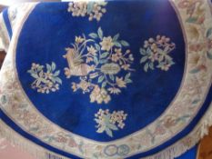 A circular Chinese fringed rug on blue ground