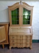 A 20th century continental blond oak serpentine fronted bureau bookcase