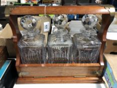 A mahogany three bottle Tantalus with brass mounts containing Edinburgh Crystal cut glass whiskey