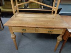 An antique pine writing table on reeded legs fitted two drawers