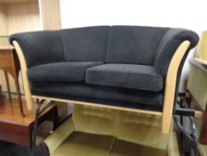 A late 20th century beech framed two seater settee upholstered in a black fabric
