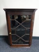 A small George III oak hanging corner cupboard with astral glazed doors