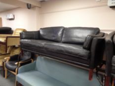 A 1970's Danish black leather three seater settee and two seater matching settee with footstool