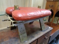 A camel stool with red leather saddle