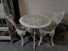 A painted cast metal patio set comprising of circular pedestal table and two chairs