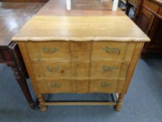 A 20th century oak serpentine front three drawer chest