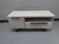 A contemporary entertainment stand fitted cupboards and drawer beneath in two-tone finish