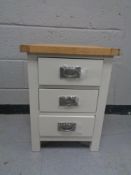 A contemporary oak topped three drawer bedside chest
