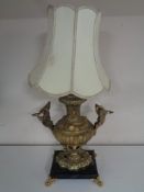 An early twentieth century ornate brass table lamp depicting swans in flight above cherubs on black
