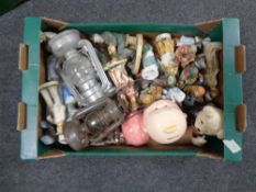 A box containing Continental figurines, oil lamps, Ringtons teddy bear, money box etc.