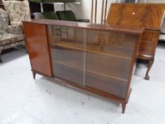 A set of mid 20th century sliding glass door bookshelves fitted a cupboard