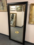 A 5' by 2' mirror in a black and gilt frame