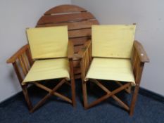 A circular teak folding garden table together with four director style chairs.