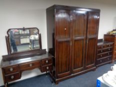 A three piece Edwardian mahogany bedroom suite comprising of triple door wardrobe,