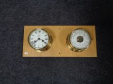 A brass cased ship's clock and barometer mounted on a board.