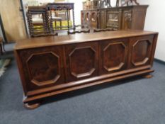 A 20th century continental oak four door low sideboard on bun feet.