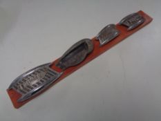 Four vintage Triumph motorcycle badges mounted on a board.