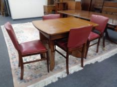 A mid 20th century walnut extending dining table together with a set of four chairs.