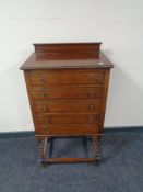 An Edwardian oak five drawer music cabinet on barley twist legs
