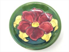 A Walter Moorcroft 'Clematis' pattern plate on green ground, Queen Mary Label, diameter 18.5cm.