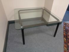 A square glass topped coffee table on painted wooden legs.