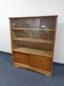 A mid 20th century sliding glass door bookcase fitted sliding doors beneath
