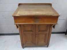 An antique oak clerk's desk fitted a double door cupboard beneath