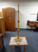 A decorative standard lamp together with a tile topped coffee table.