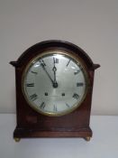 An Edwardian bracket clock with silver dial by Whittaker of Oldham on raised brass feet.