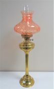 A 19th century brass oil lamp with pink glass shade and chimney,
