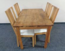 A contemporary pine kitchen table together with a set of four rail backed chairs
