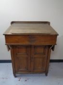 An antique oak clerk's desk fitted a double door cupboard beneath