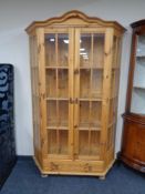 A shaped pine double door display cabinet fitted drawer beneath