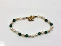 A pearl and malachite necklace with gold spaces and clasp.