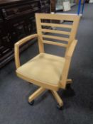 A contemporary swivel office armchair in an oak finish.
