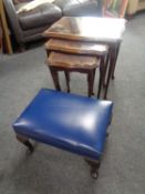 A nest of three mahogany glass topped tables and a leather upholstered footstool
