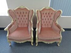 A pair of cream painted wood framed French style wing back armchairs upholstered in a pink button