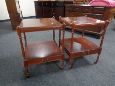 A pair of Regency style two tier occasional tables on castors