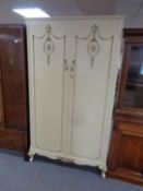 A cream and gilt double door wardrobe.