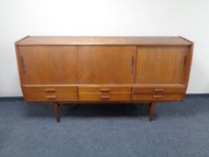 A mid 20th century teak sliding door sideboard, fitted six drawers beneath, on raised legs.