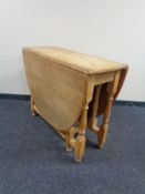 A blonde oak gate leg table.