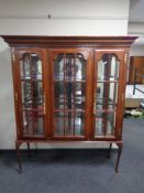 A triple door bookcase with brass mounts on Queen Anne style legs.