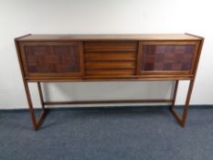 A six piece teak dining room suite comprising sliding door sideboard on raised legs,