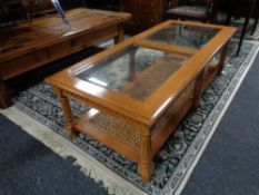 A contemporary rectangular coffee table with two glass inset panels and wicker shelf beneath