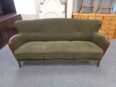 A mid 20th century wood armed three seater settee upholstered in a green button back fabric