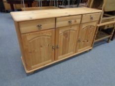A contemporary pine triple door sideboard fitted three drawers above